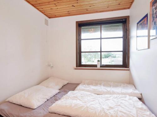 two beds in a small room with a window at 6 person holiday home in Bl vand in Blåvand