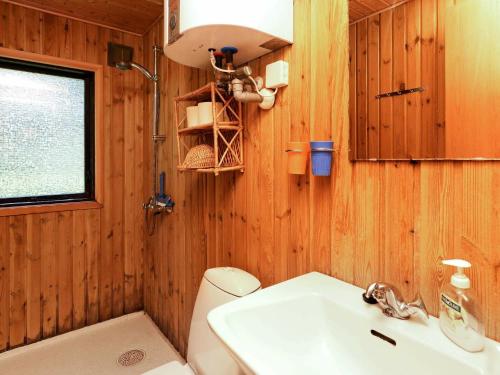 ブロックフスにあるThree-Bedroom Holiday home in Blokhus 21のバスルーム(トイレ、洗面台付)、窓が備わります。