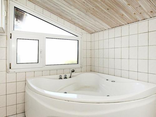 GrønhøjにあるThree-Bedroom Holiday home in Løkken 65の窓付きのバスルーム(白いバスタブ付)