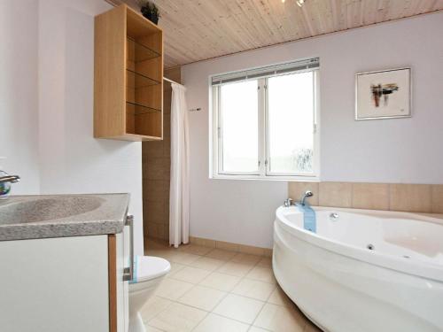 Fjand Gårdeにある8 person holiday home in Ulfborgのバスルーム(バスタブ、トイレ付)、窓が備わります。