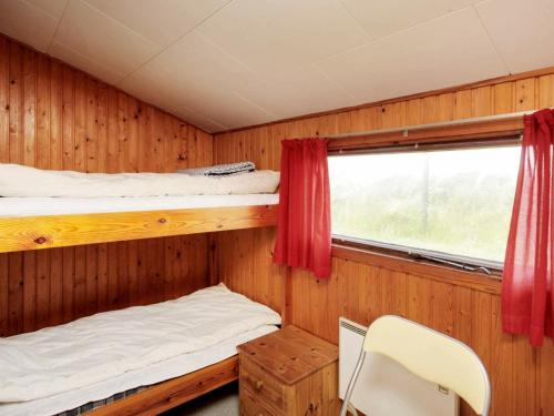 a bedroom with two bunk beds and a window at Two-Bedroom Holiday home in Løkken 25 in Grønhøj