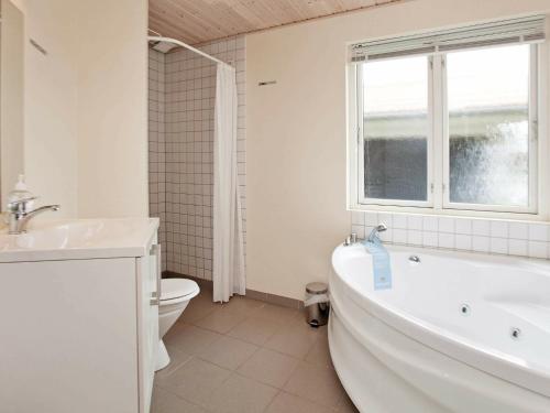 a bathroom with a tub and a toilet and a window at 8 person holiday home in Ulfborg in Fjand Gårde