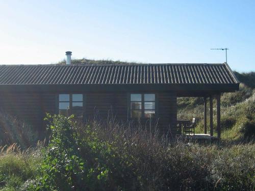 uma cabana de madeira com um banco à frente em 6 person holiday home in Hirtshals em Hirtshals