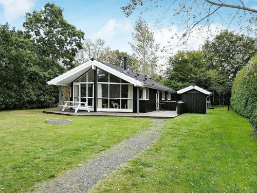 ein kleines Haus auf einem Feld mit einem Rasenplatz in der Unterkunft 8 person holiday home in Hadsund in Øster Hurup