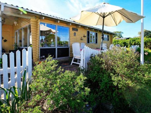 4 person holiday home in Snedsted في Snedsted: منزل به سياج أبيض ومظلة