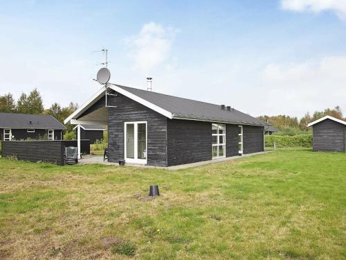 una casa negra con un campo de hierba delante de ella en 6 person holiday home in Hals en Hals