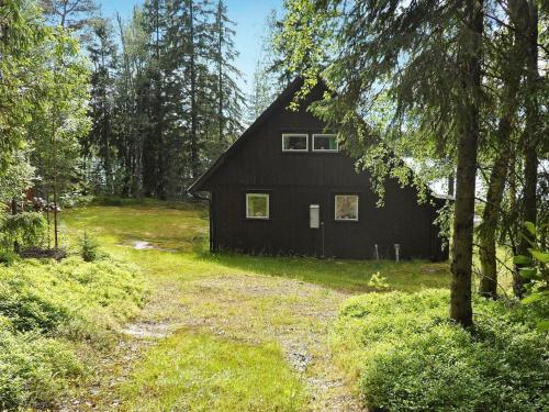 a black house in the middle of a forest at 5 person holiday home in L GDE in Himmersundet