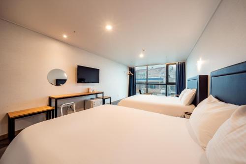 una camera d'albergo con due letti e una televisione di Sunrise Hotel Supjikoji a Seogwipo