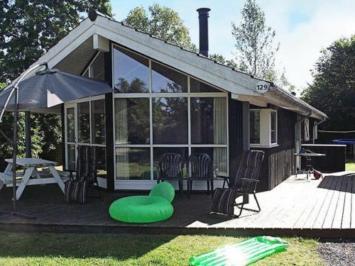 uma casa com um repousa-pés verde sentado num deque em 8 person holiday home in Hadsund em Øster Hurup