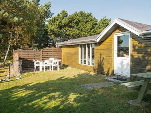 a small yellow house with a table and chairs in a yard at 6 person holiday home in Fan in Fanø