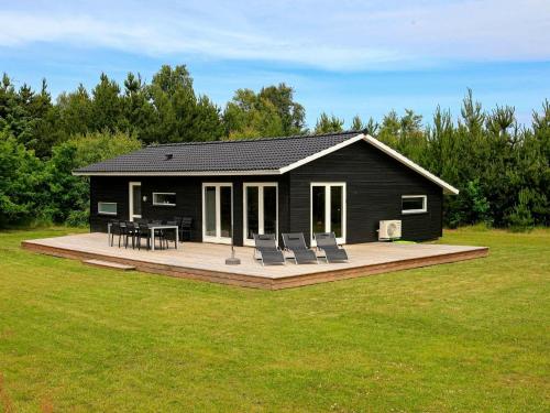 a small black house with chairs and a deck at 6 person holiday home in Strandby-By Traum in Strandby