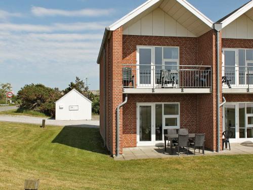 a brick house with a balcony and a table and chairs at 6 person holiday home in H jer in Emmerlev