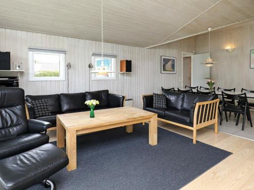 Spodsbjergにある8 person holiday home in Rudk bingのリビングルーム(黒革の家具、テーブル付)