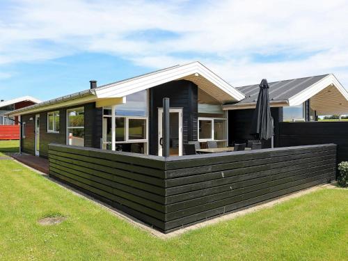 a black house with an umbrella in a yard at 6 person holiday home in Tranek r in Tranekær