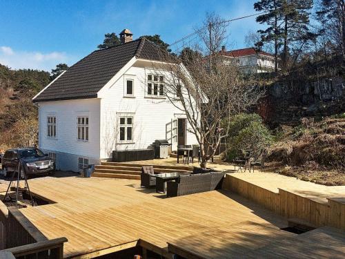 a white house with a wooden deck in front of it at 7 person holiday home in Høvåg in Høvåg