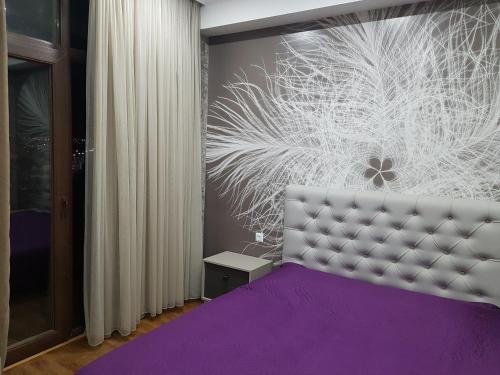 a bedroom with a purple bed and a wall with a painting at Your home in Kutaisi