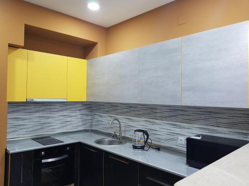 a kitchen with a sink and yellow and gray cabinets at Your home in Kutaisi