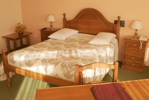 Hotel Xallas في Santa Comba: غرفة نوم بسرير كبير وموقف ليلتين