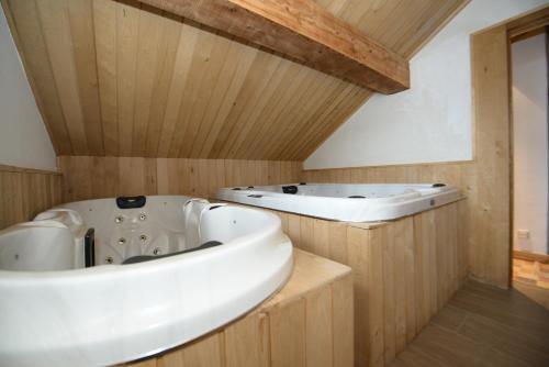 - 2 baignoires dans une salle de bains avec des murs en bois dans l'établissement Chalet La Becca, à Le Fornet