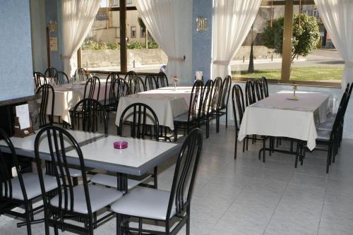 Hotel Xallas في Santa Comba: غرفة طعام مع طاولات وكراسي مع مفارش بيضاء