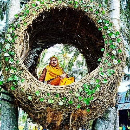 a woman sitting in a nest in a tree at Homestay Damai Sri Kota in Kepala Batas