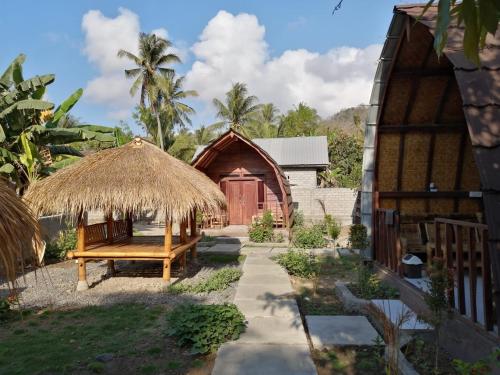 un banco frente a un edificio con una cabaña en Bale Hostel, en Kuta Lombok