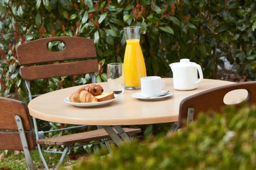 a table with a plate of bread and a bottle of orange juice at Campanile Nevers Nord - Varennes-Vauzelles in Varennes Vauzelles