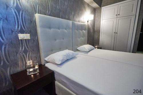 a bedroom with a large white bed with a night stand at Atlantic Hotel in Athens