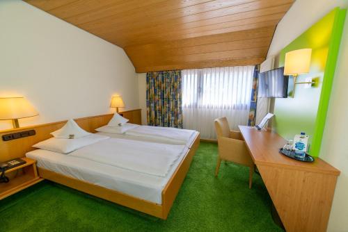 a hotel room with a bed and a desk at Stadt-gut-Hotel Filderhotel in Ostfildern