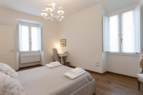 a white bedroom with a bed and a table and windows at Mercatale Apartment in Prato