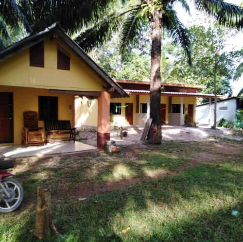 a yellow house with a palm tree in front of it at Som PalmGarden in Ko Lanta