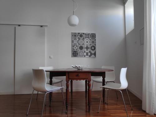 uma sala de jantar com uma mesa de madeira e cadeiras brancas em Casa do Arco, Santarém em Santarém