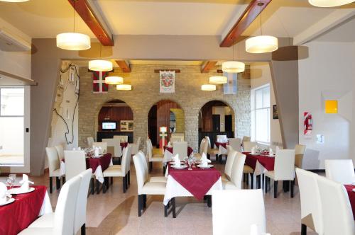 un restaurant avec des tables blanches, des chaises et des nappes rouges dans l'établissement Hotel Euzko Alkartasuna, à Macachín