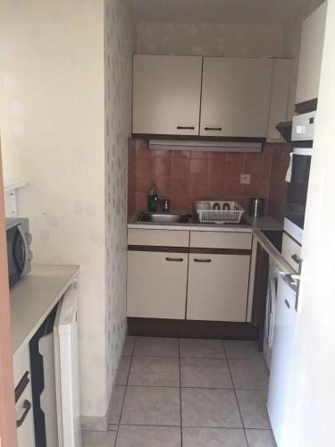 une petite cuisine avec des armoires blanches et un évier dans l'établissement Fréjus plage T2, piscine, parking, plages à 200m, à Fréjus