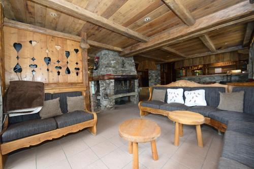 a living room with couches and a stone fireplace at Chalet La Becca in Le Fornet
