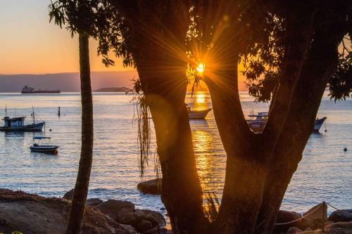 a sunset over a body of water with boats at Fauna in Praia do Bananal