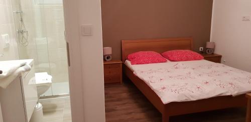 a bedroom with a bed with two red pillows and a shower at Bed and breakfast Nika in Rab