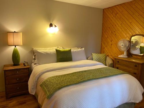 a bedroom with a bed with white sheets and green pillows at Chalets et Studios Le Vent Du Nord in Lac-Superieur