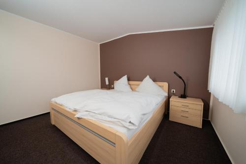 a bedroom with a bed with white sheets and a night stand at Hotel Emshof in Warendorf