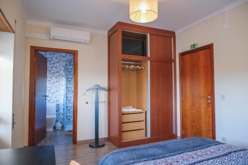 Schlafzimmer mit einem Bett und einem Holzschrank in der Unterkunft Alojamento Local do Arado in Bragança