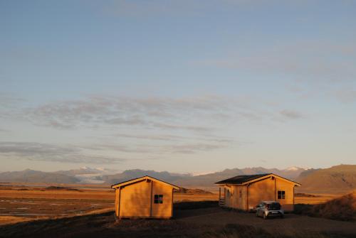 two buildings with a car parked in the middle of a field at Miðsker 1 in Höfn