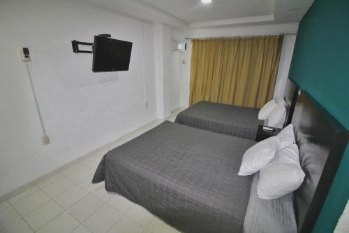 a hotel room with two beds and a flat screen tv at EMS Hoteles Boca del Río in Veracruz