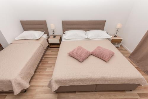 two beds with pillows on them in a bedroom at Apartments Nina M in Baška Voda
