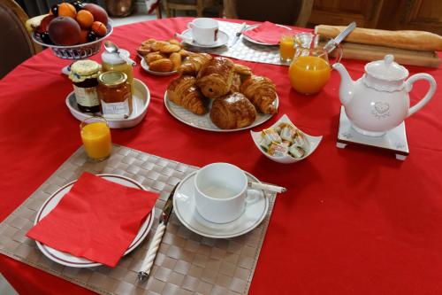 a table with a red table cloth with breakfast foods at Maison D'Hôtes Du Théâtre in Douai