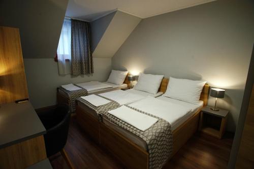 a small room with two beds and a window at Dolce Vita Panzió in Miskolc