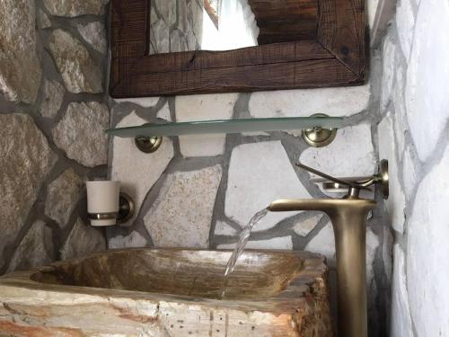 Baño de piedra con lavabo y espejo en Casa Lisetta, en Villa D'agri