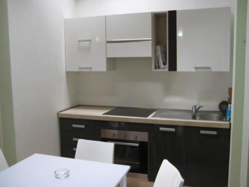 a kitchen with white cabinets and a sink and a table at Garibaldi 4 Loft in Brescia