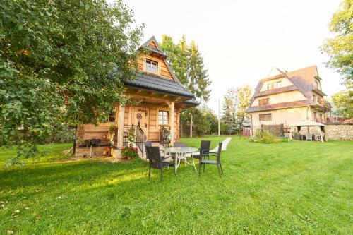 a table and chairs in front of a house at Apartamenty nad Młynówką in Chochołów