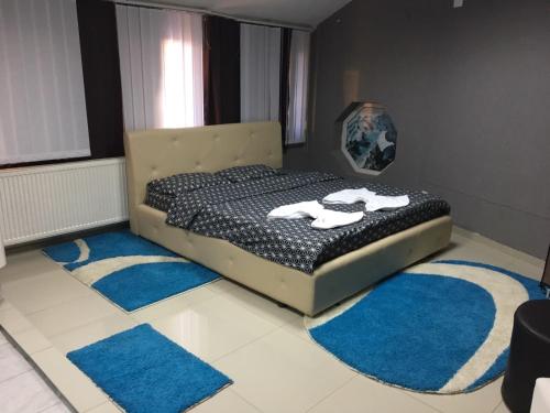 a bedroom with a bed with blue rugs on the floor at Family White Hotel in Gjilan