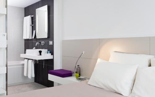 - une chambre avec un lit, un lavabo et un miroir dans l'établissement Novotel Suites Paris Issy Les Moulineaux, à Issy-les-Moulineaux